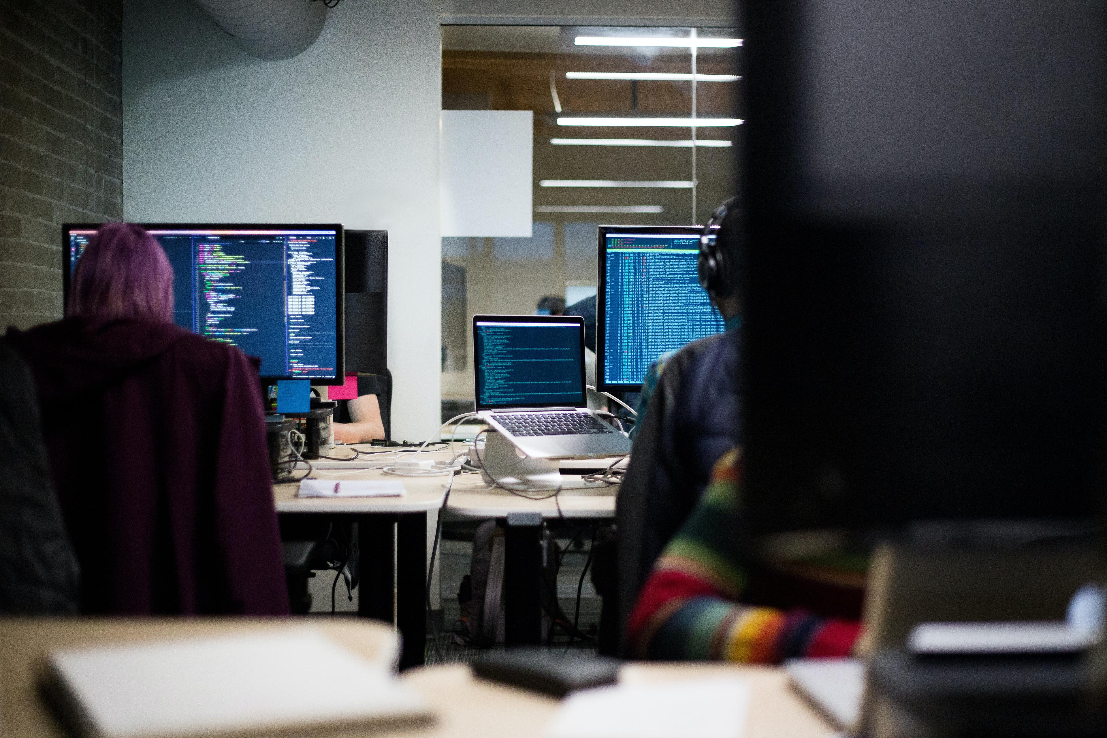 cover picture has a background with monitors that displays some code and people are working in the computers